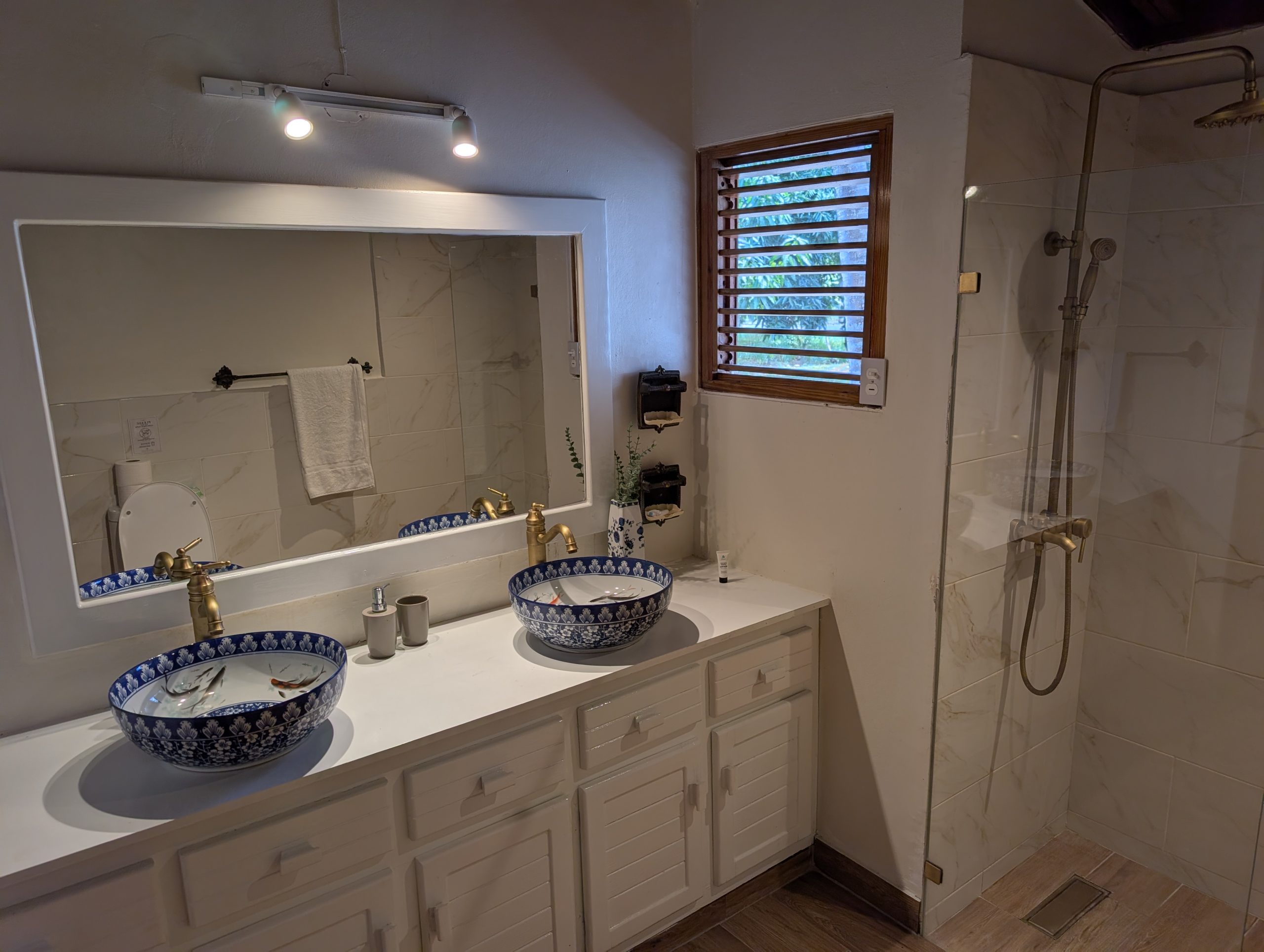 Baño terminado de la villa con doble lavamanos sobre encimera y ducha de vidrio